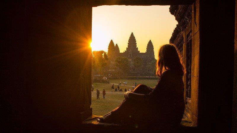 a lady is watching the sunset from a corridor inside Angkor Wat