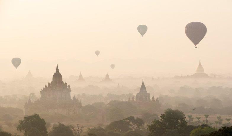 hot air ballons on top of temples in a foggy day