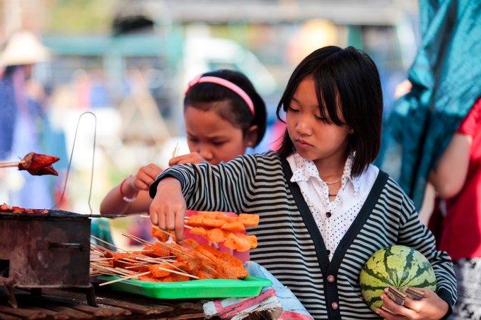 two local children are buying food from a street food stall at Inle market
