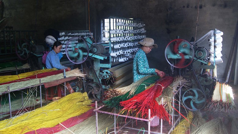 two women are weaving sedge mats