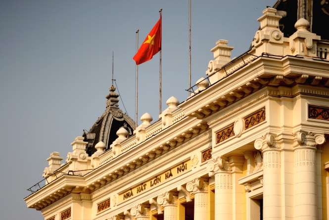 a Vietnamese national flag flying on top of Hanoi Opera House