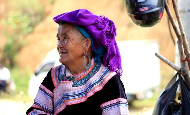 a smiling old lady with a purple scarf around her head